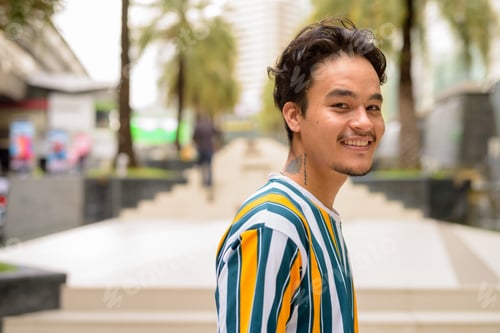 Preview: Portrait of handsome multi-ethnic young man wearing colorful shirt outdoors during summer and
