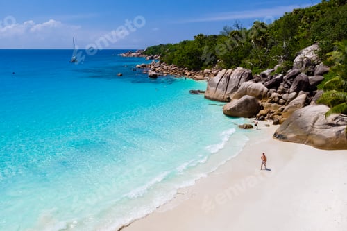 Preview: young man on a white beach with turquoise colored ocean, Anse Lazio beach Praslin Island Seychelles