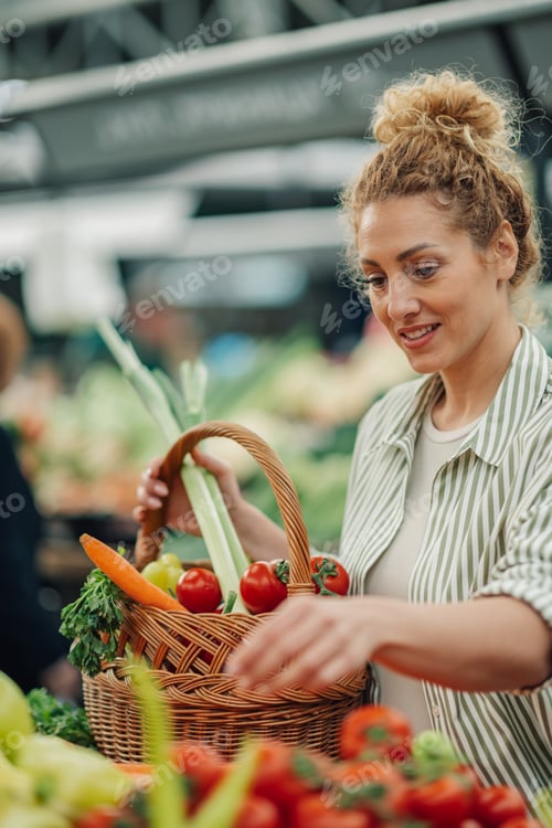 Preview: Smiling woman with basket in hands buying fresh produce at market.