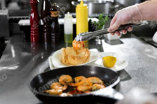 Preview: Chef roasts prawns in a frying pan.