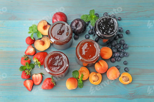 Preview: Different jams in jars and ingredients on blue wooden table, flat lay