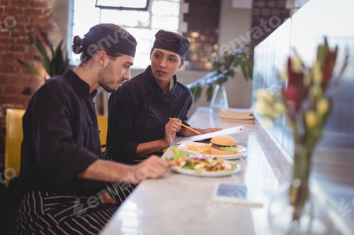 Preview: Young wait staff discussing over clipboard and food while sitting at counter
