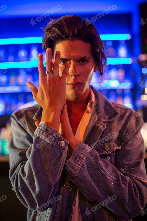Preview: Portrait of young man in jean jacket with bar background.