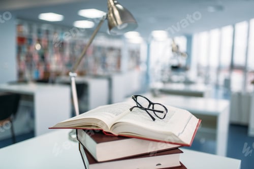 Preview: Stack of books and glasses on table in library