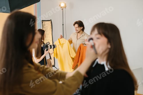 Preview: Backstage from a studio photo shoot. Photographer and make-up artist work with professional models.