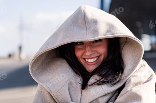 Preview: joyful young woman hiding under her coat hood