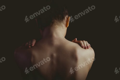 Preview: Nude woman with a shoulder injury on black background