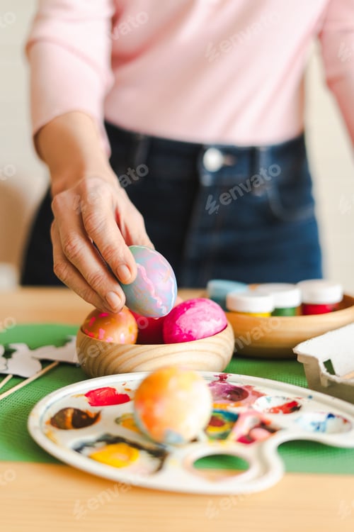 Preview: Woman's hand holding painted Easter egg, preparing for spring holiday celebration