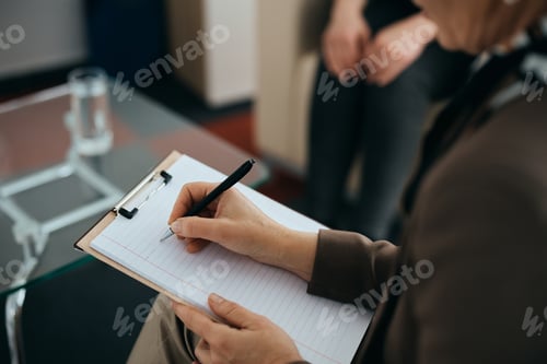 Preview: Close-up of mental health professional taking notes during counseling with a patient.