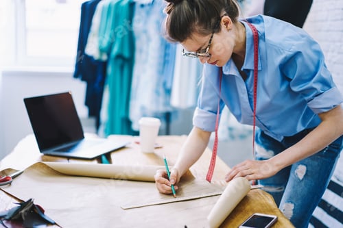 Preview: Tranquil female dressmaker working with pattern in atelier