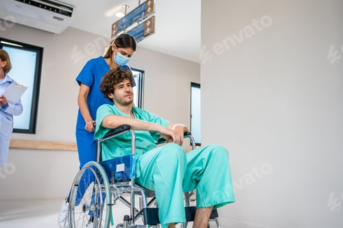 Preview: Caucasian doctor support patient sit on wheelchair in hospital hallway.