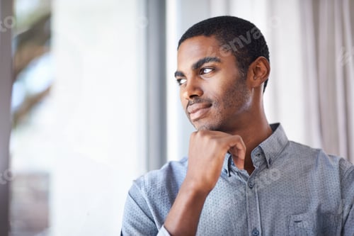 Preview: Hes got a lot on his mind. Shot of a handsome young man thinking while looking through the window.