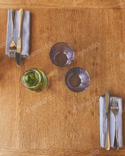 Preview: Empty glasses by bottle with mint water and cutlery on table