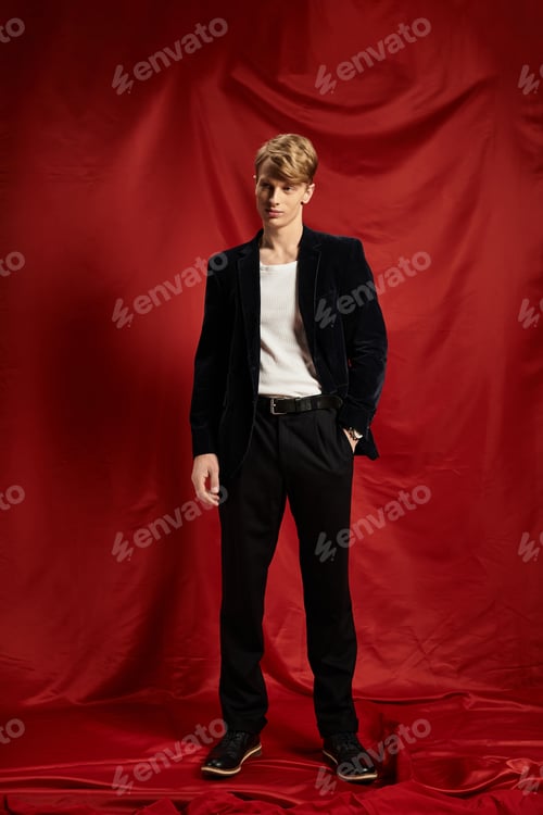 Preview: Young man embodies modern masculinity with alluring style against vibrant red backdrop