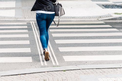 Preview: Young woman wearing casual clothes on zebra crossing. Rear view.