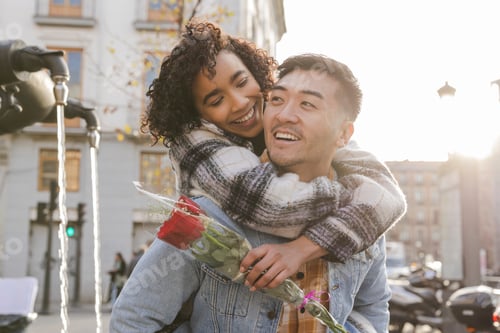 Preview: Happy multiracial couple celebrating valentine's day with red roses and piggyback ride