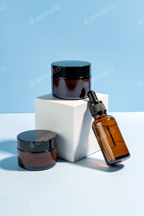 Preview: Cosmetics packaging. Set of different cosmetic bottles of cream or serum on a white cube podium. B
