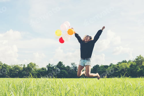 Preview: young beautiful asian woman holding balloon on green grassland running and jumping enjoy fresh air