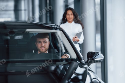 Visualização: Recém possuído. Cliente masculino e empresária moderna no salão de automóveis