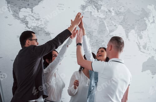 Vista previa: Celebrating success. Team of freelancers standing against wall with map of the world on it