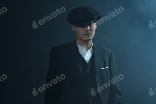 Preview: Retro 1920S English Gangster Wearing Suit And Flat Cap Standing In Smoky Room. Peaky Blinders Style.