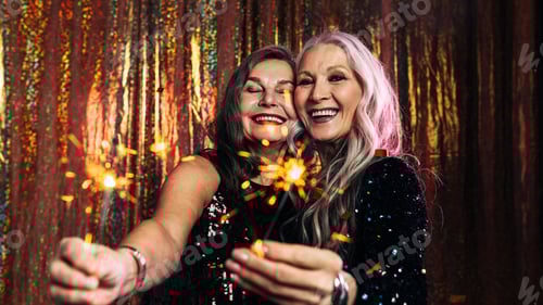 Preview: Two senior girlfriends having fun together holding sparklers