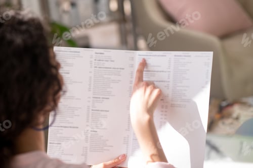 Preview: Pretty curly-haired woman pointing to the list with her finger