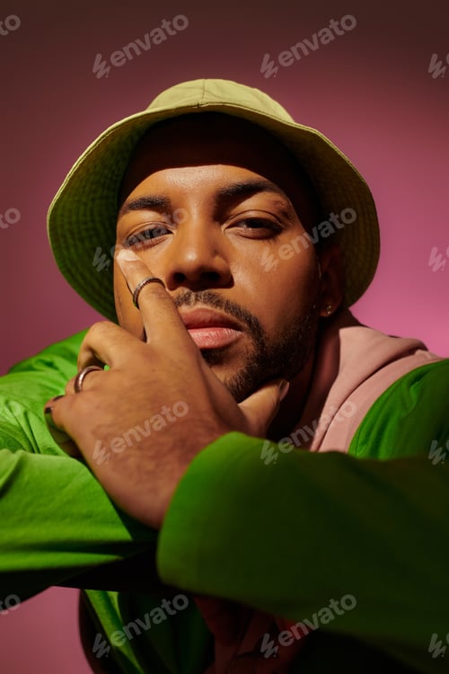 Preview: good looking man in casual attire with rings and earring looking at camera, fashion concept