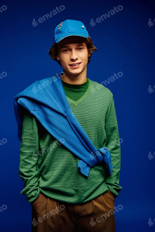 Preview: Fashion forward young man showcasing casual trendy style against a vibrant blue backdrop