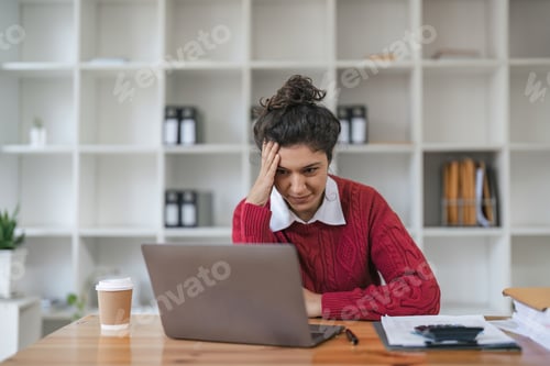 Preview: Stressed business woman working from home on laptop looking worried, tired and overwhelmed.
