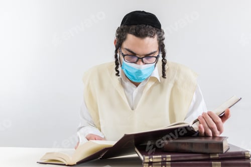 Preview: Young orthodox Jew with a face mask studying religious texts - concept of the new normal