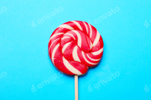 Preview: Tasty striped lollipop on light blue background, top view