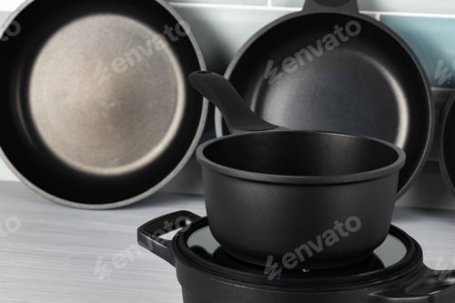Preview: New black cookware against blue tile wall