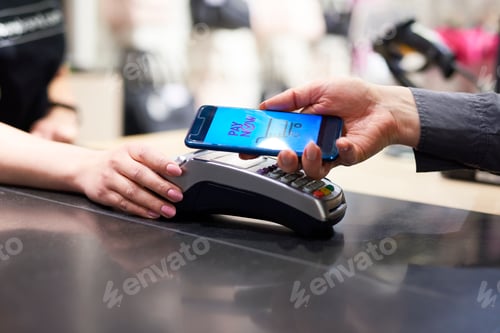 Preview: Woman's hand with mobile phone paying at checkout
