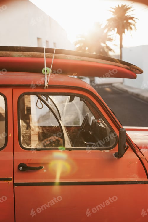 Preview: A stack of surfboards on a retro car roof with sun shining. Summer and surf background wallpaper.