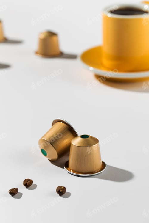 Preview: Coffee capsules with a cup and saucer in the background