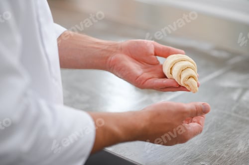 Preview: A male baker makes croissants in the bakery kitchen
