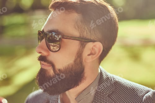 Preview: Bearded male with a stylish haircut in casual clothes in a park.