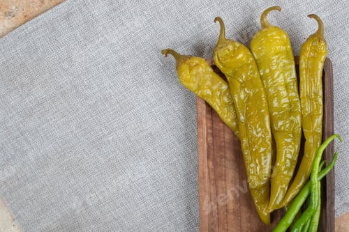 Preview: Pickled and fresh green peppers on wooden board