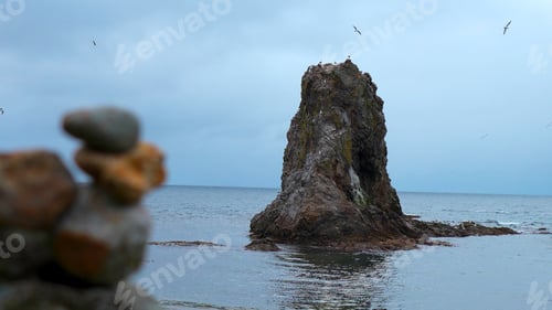 Preview: Stones on shore against background of cliff in sea. Clip. Stacked stones on rock background with