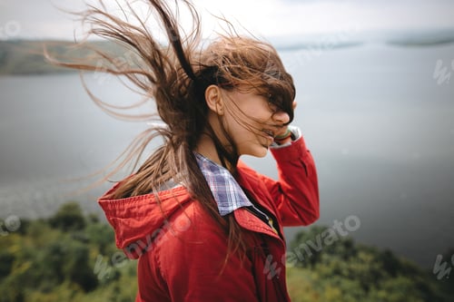 Preview: Young carefree woman in glasses relaxing on cliff