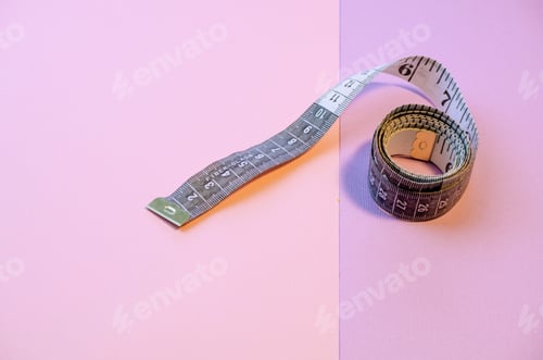Preview: measuring tape lies on a pink background