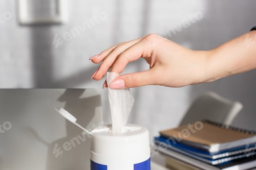 Preview: Cropped view of woman taking cleansing napkin near laptop and notebooks on blurred background
