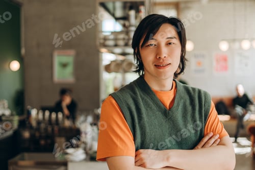 Preview: Confident barista posing with crossed arms in his coffee shop