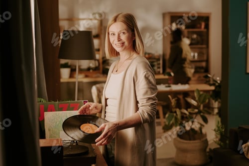 Preview: Senior Caucasian Woman Smiling While Playing Vinyl Record in Cozy Living Room