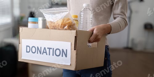 Preview: Woman volunteer holding food donation box at home