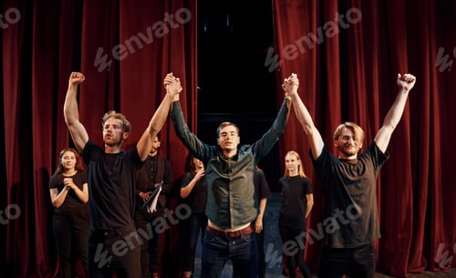 Preview: Conception of success. Group of actors in dark colored clothes on rehearsal in the theater