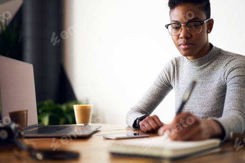 Preview: Focused female manager writing thoughts in notebook during work