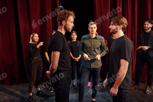 Preview: Eye contact practice. Group of actors in dark colored clothes on rehearsal in the theater