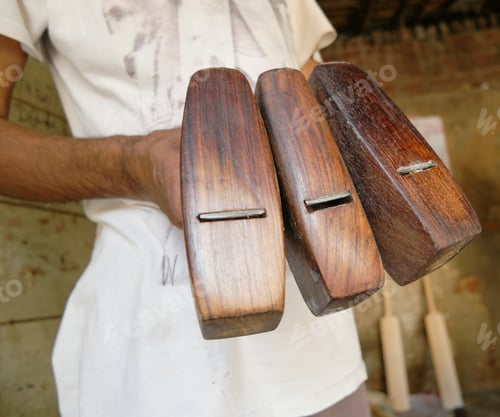 Preview: Closeup shot of a male's hands holding wooden objects in a factory for a cricket bat in Delhi, India